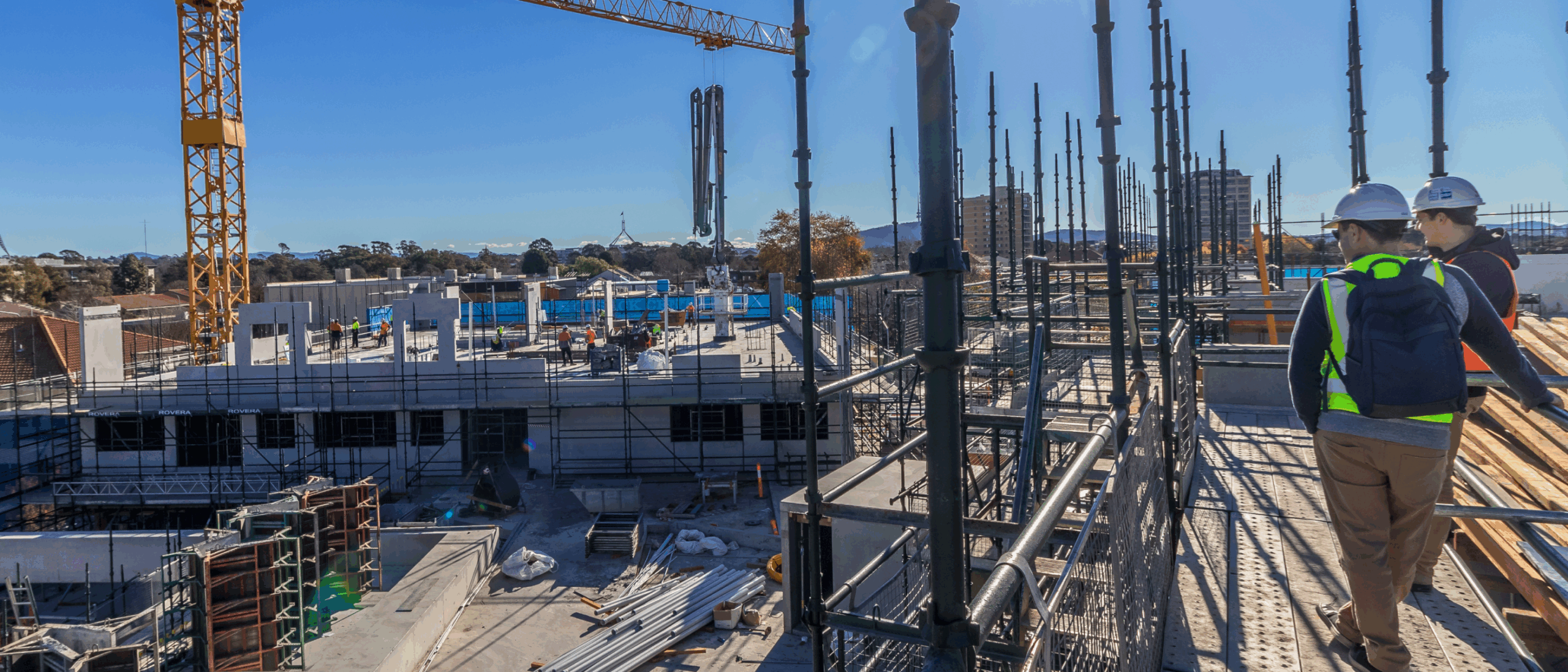 Two construction workers in high vis, wearing hard hats on site representing safe practices for Safe Work Month