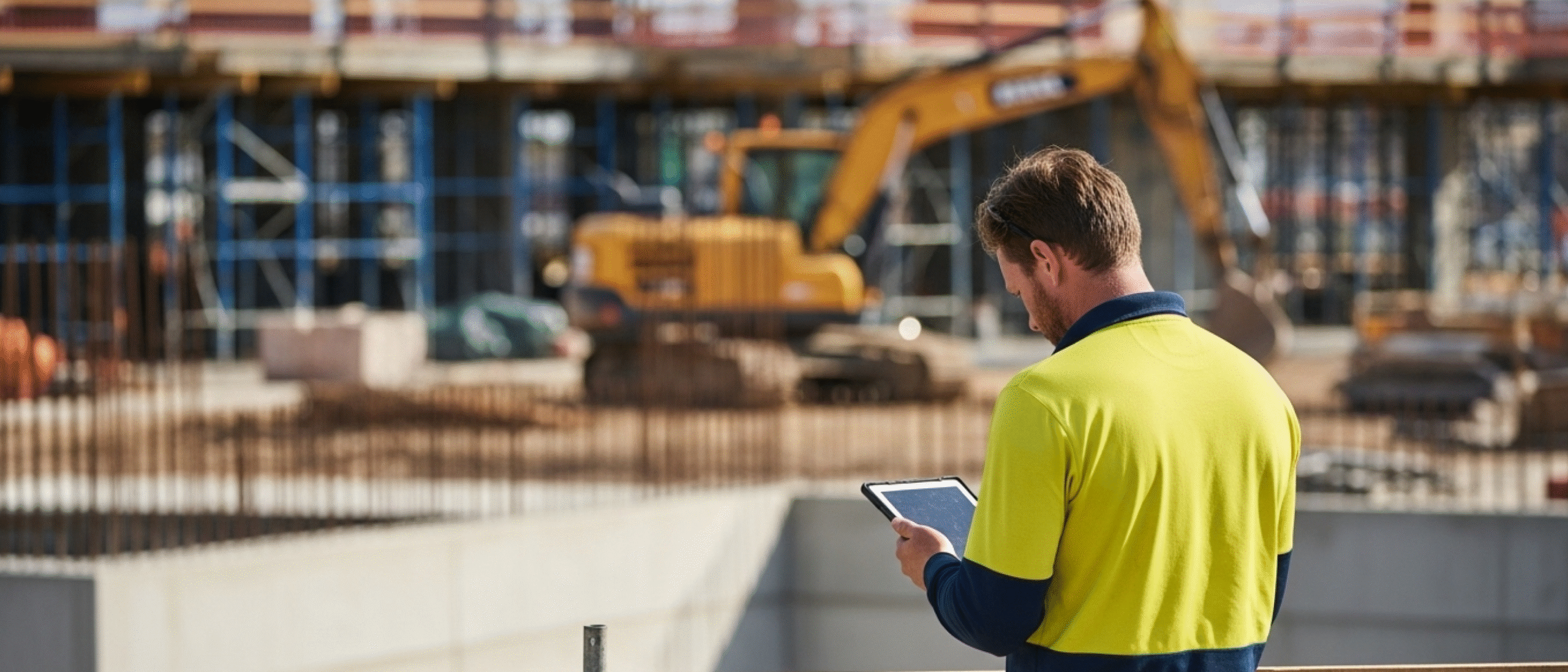 Construction manager using a tablet on an active job site, illustrating construction management software costs and digital project oversight in the field.
